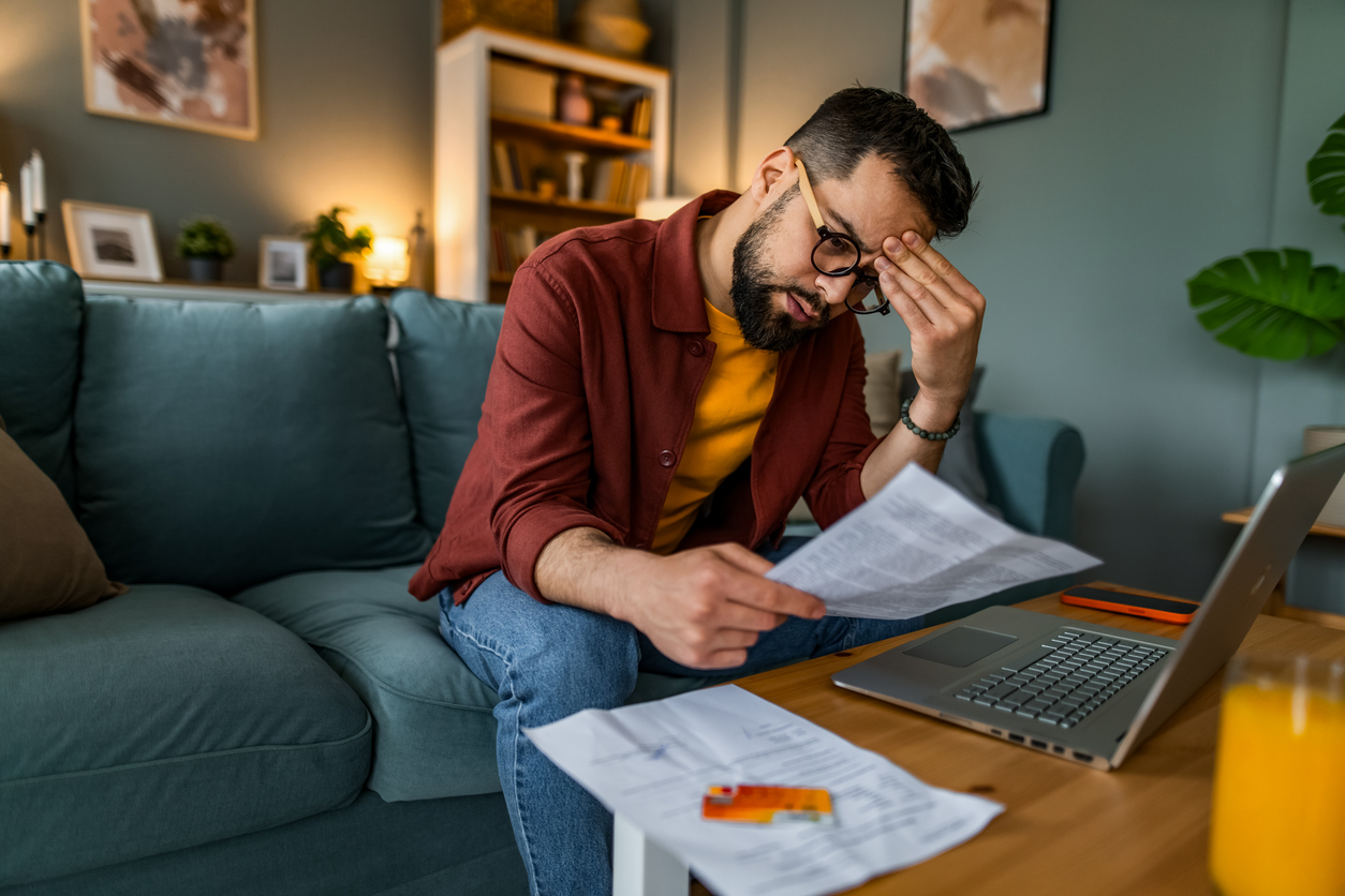 Worried man managing budget and paying bills and taxes at home.