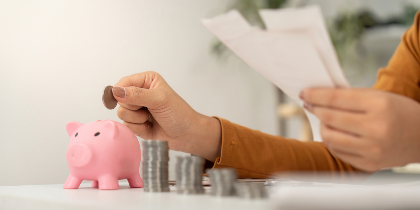 Financial Planning: Woman Adding Coins to Piggy Bank